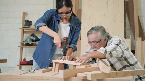 Carpenter woman use electric drill to drill wood