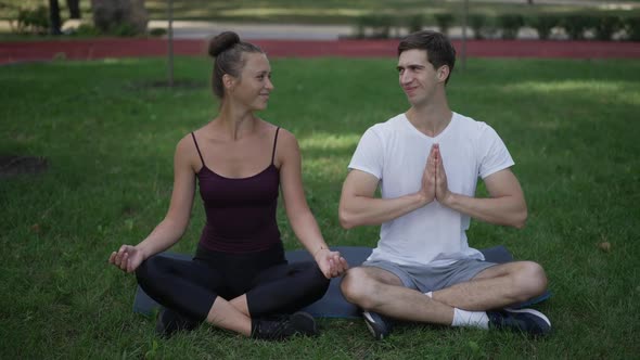 Wide Shot of Happy Confident Caucasian Boyfriend and Girlfriend in Lotus Pose Smiling Closing Eyes