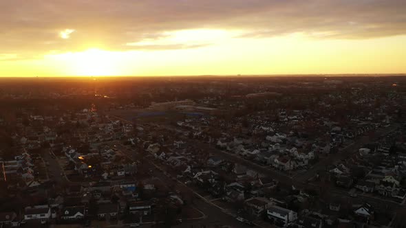 A high angle, aerial view over a Long Island neighborhood during a golden sunrise. It was shot with