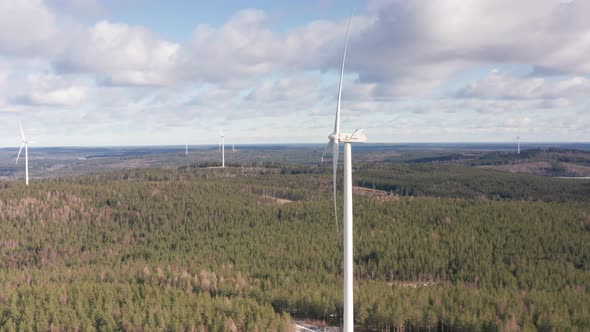 AERIAL - Wind turbines in a forest wind power farm, Sweden, wide circle shot