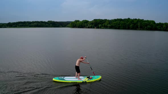 Handsome young man on sup paddle standing board