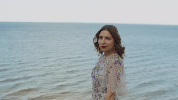 Attractive Woman with Red Lips and Curly Hair Smiling at Camera Blue Sea with Waves and Blue Sky in