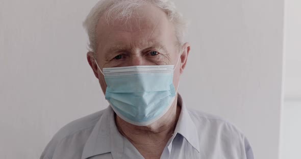 Senior Man Wore in Medical Mask Speaking Emotionally with Gestures at Camera