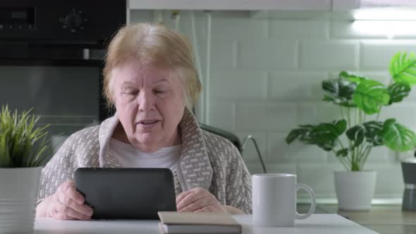 Happy Elderly Woman with Digital Tablet Having Video Call at Home