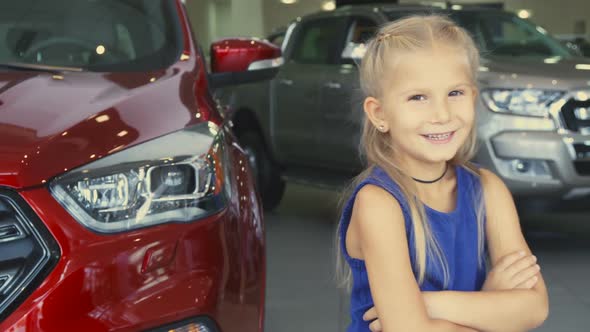 A Sweet Girl Stands on the Background of the Car and Laughs