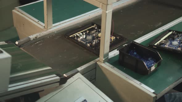 worker checks an electronic board after soldering at a TV factory