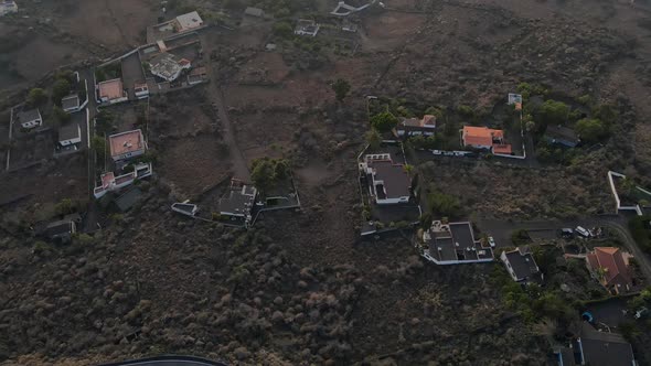 Drone flying over rural village covered with volcanic ash on La Palma island. Aerial top-down forwar