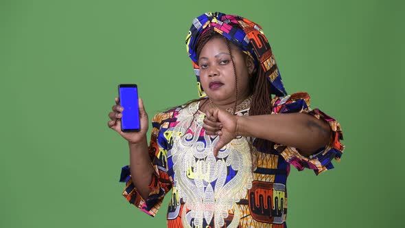 Overweight Beautiful African Woman Wearing Traditional Clothing Against Green Background