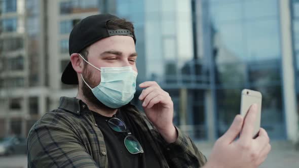 Man in Casual Clothes in Medical Mask Chatting Online on Smartphone's Camera