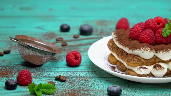Portion of Classic Tiramisu Dessert with Raspberries and Blueberries on Wooden Background