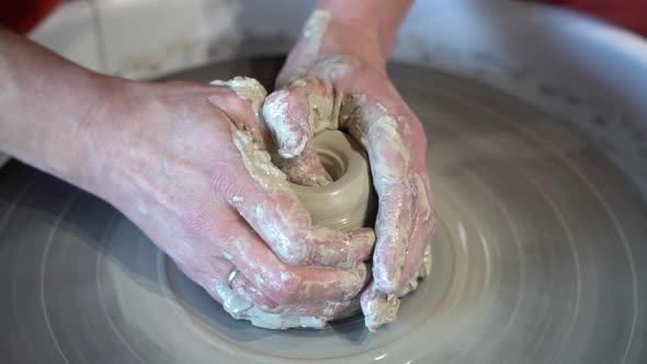 Clay jar being sculpted on a potters wheel by female hands, Close up view
