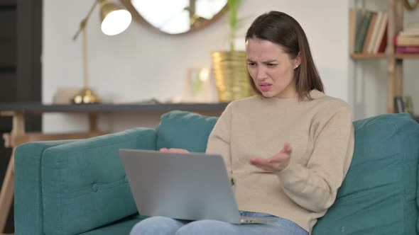 Young Woman with Laptop Reacting to Failure on Sofa