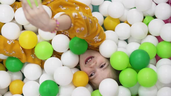 a Little Girl Plays in a Dry Pool with White Yellow and Green Plastic Balls
