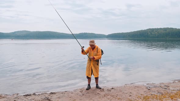 A Man Holding a Fishing Rod and Walks Away From the Shore