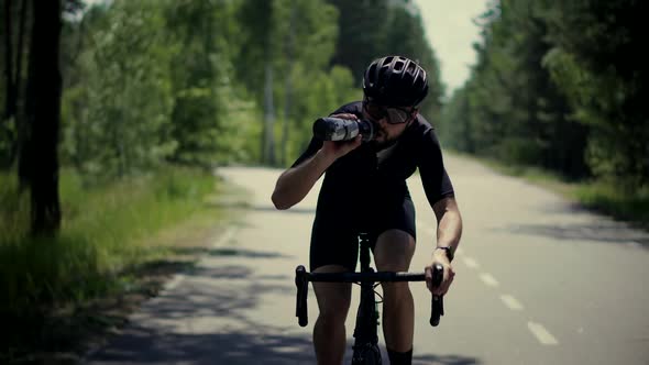 Cyclist Fitness Riding On Road Bike And Drinking Water.Triathlon Cycling Workout.Fit Athlete Workout
