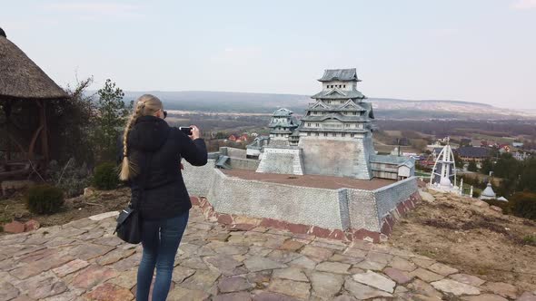 Woman Takes a Photo Near a Miniature Chinese Japanese Pagoda. Park of Miniatures.