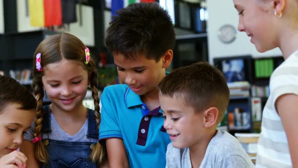 Smiling school kids using digital tablet in classroom