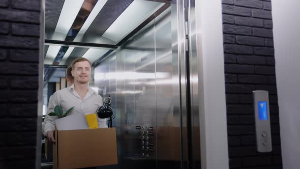 A Man Holds a Box with His Belongings in the Elevator