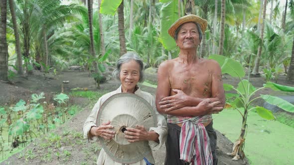 Portrait of senior elder couple smiling to camera with happy face after working in the coconut farm.