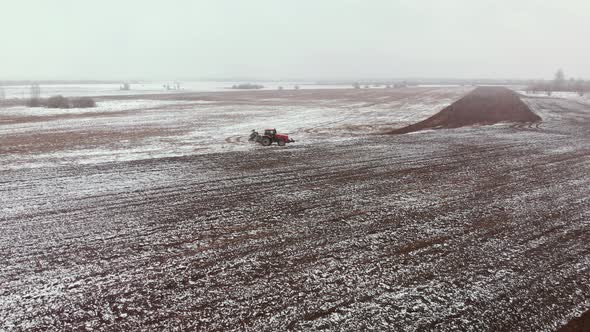 Tractor Plows Snowcovered Farmland in Spring
