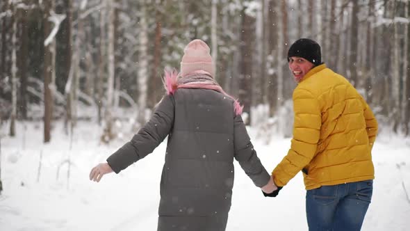 A Young and Beautiful Couple Is Having Fun in the Park, Running and Holding Hands. Valentine's Day