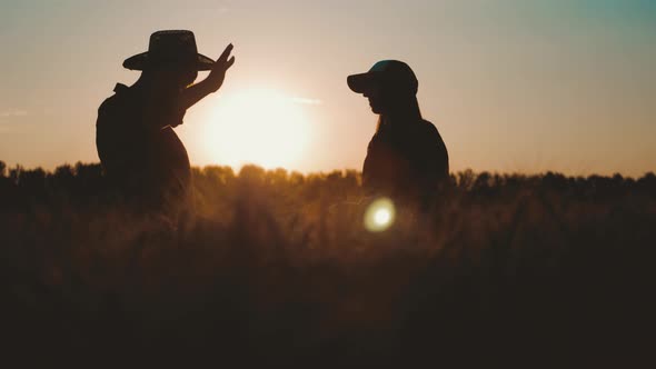 Team Farmers Stand in Wheat Field Holding Tablet and Use Technology To Predict the Future