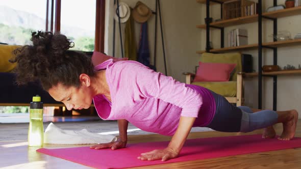 Mixed race woman practicing yoga on yoga mat at home