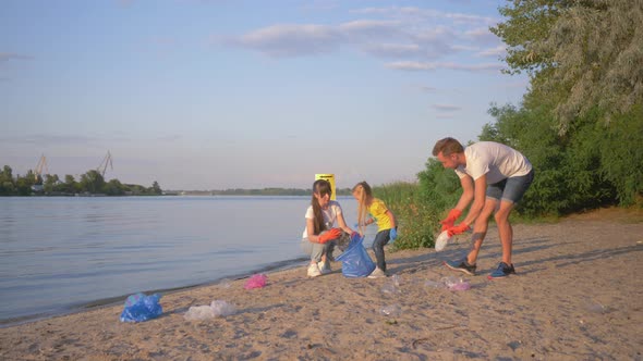 Family of Volunteers, Young Father and Mother with Little Daughter Collects Refuse in Garbage Bag on