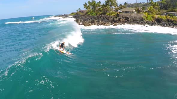 Aerial view of a man sup stand-up paddleboard surfing in Hawaii.