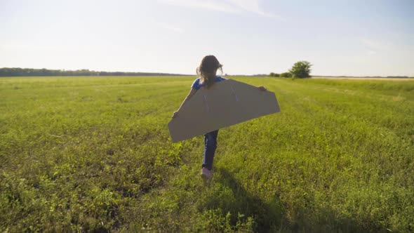 Little Girl Child Running On The Field With Wings Behind Back