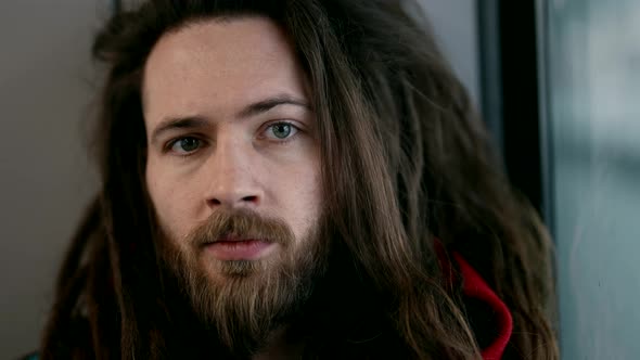 Young Hipster Guy with Trendy Hairstyle with Dreadlocks Looking at Camera Close Up of Face