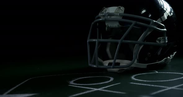 American football head gear on green board with strategy drawing