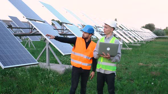 Two Engineers with a Laptop on the Solar Farm, Standing in a Special Uniform.