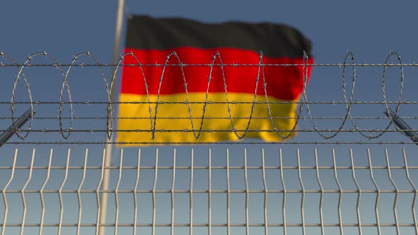 Blurred Waving Flag of Germany Behind Barbed Wire
