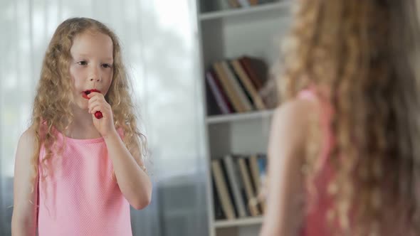 Little Girl Putting on First Make-Up, Playing with Lipstick in Front of Mirror