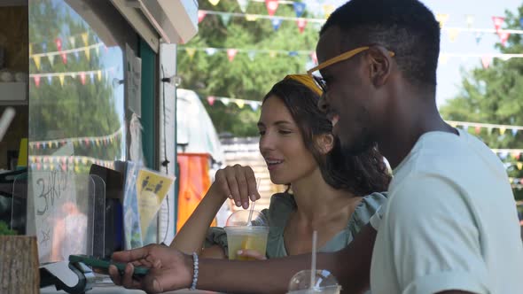 AfroAmerican Man Pays with Phone Talks to Brunette Woman