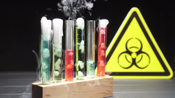 Glass Test Tubes with Boiling Liquid of Different Colors Against the Background of the Biohazard