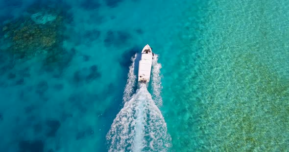 Aerial drone view of a motor boat going to a scenic tropical island in the Maldives.