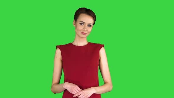 Model Woman in Red Dress Presenting Something Showing with a Hand on Some Object on a Green Screen