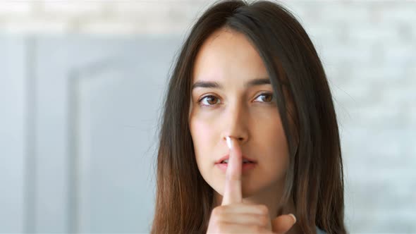 Young Pretty Woman Making Silent Gesture with Finger on Lips