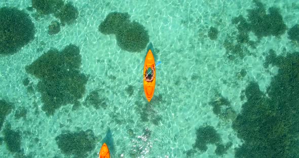 Aerial drone view of a man and woman couple kayaking around a tropical island