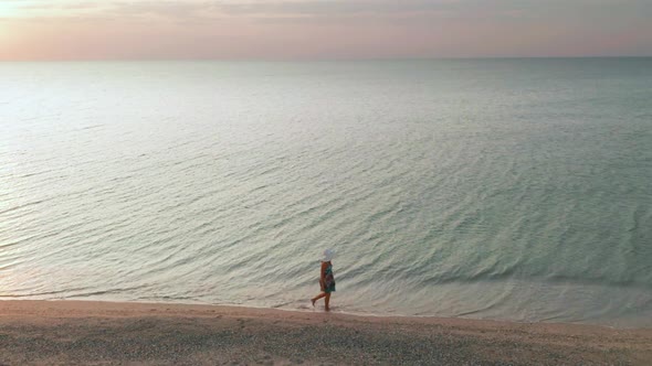 Beautiful Scene of a Woman Walking on Ocean Beach at Sunset