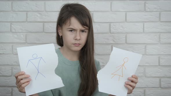 Sad child with a picture of parents.