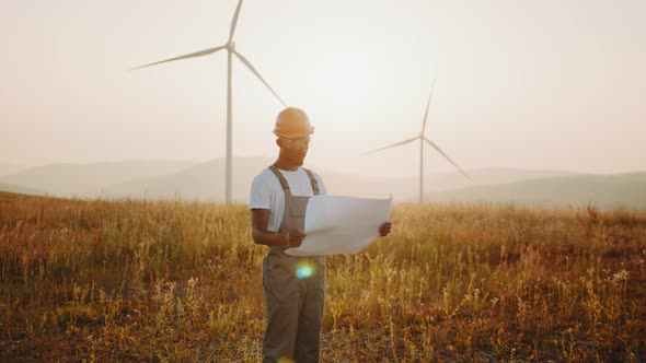 Focused African American Man with Blueprints in Hands Standing Among Farm with