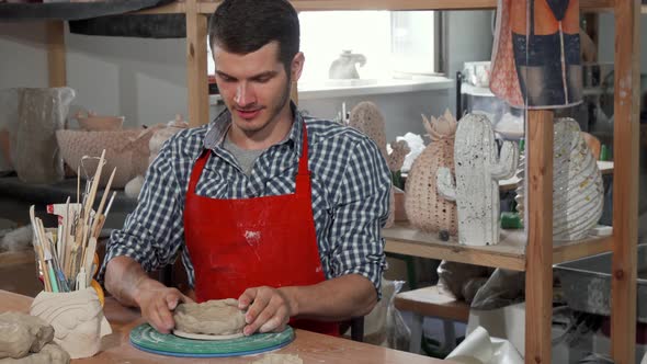 Young Male Ceramics Artist Smiling To the Camera While Working