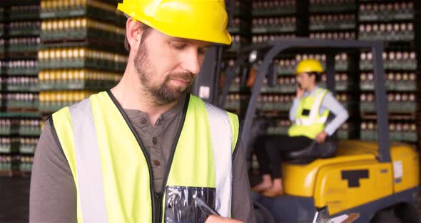 Male supervisor maintaining record on clipboard in warehouse