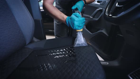 A Worker Cleans the Interior of a Car with a Washing Vacuum Cleaner