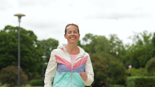 Smiling Woman Running Along Park 