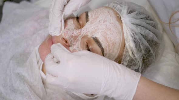 Doctor Beautician Removes White Cream From the Face of His Patient Lying