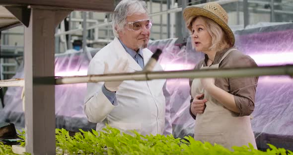 Portrait of Senior Caucasian Female Agronomist Talking with Professional Male Scientist